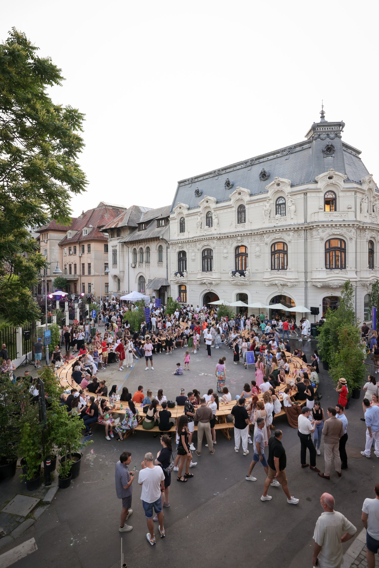 Intersecția plină de oameni la apus, cu fațada casei La Mița Biciclista în fundal